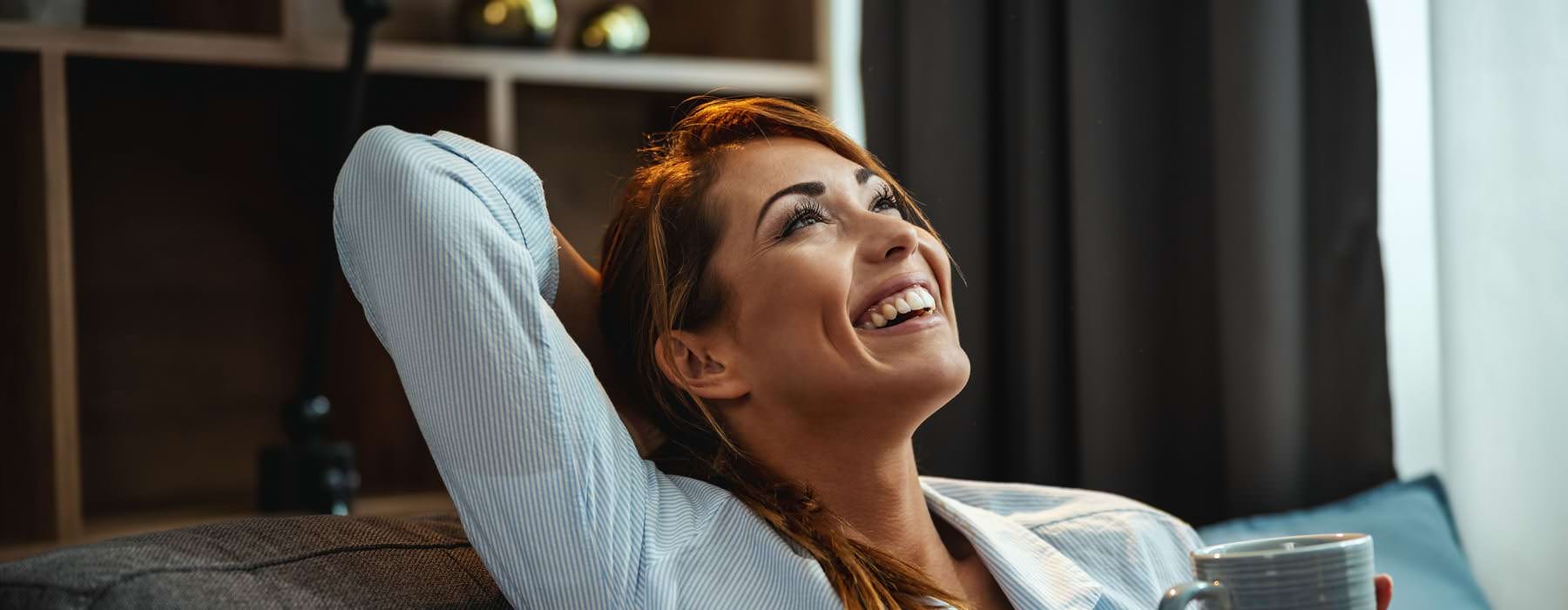 a woman laughing while holding a cup