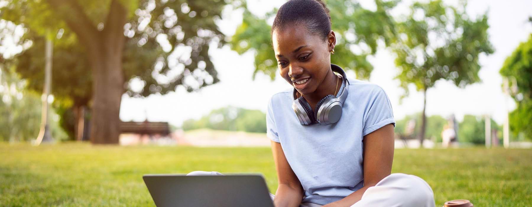 a person sitting on the grass using a laptop